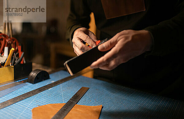 Geschnittener Handwerker beim Schärfen eines Messers in der Werkstatt