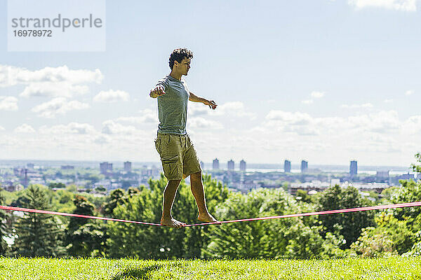 Sportlicher Mann beim Versuch  eine Slackline zu spannen