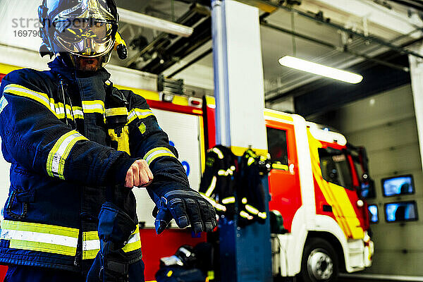 Feuerwehrmann zieht Handschuhe an  um zu einem Notfall zu gehen