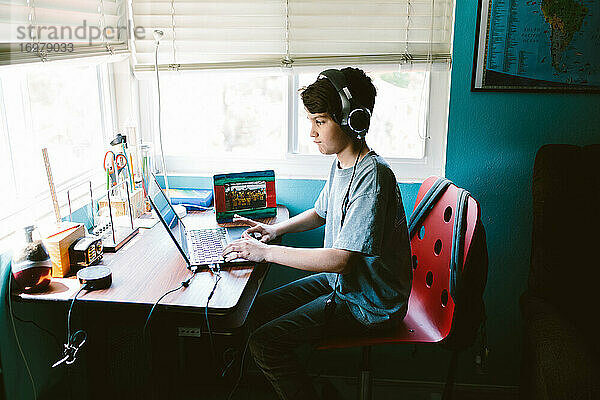 Junge sitzt am Schreibtisch und besucht seine Zoom-Klasse während der Pandemie