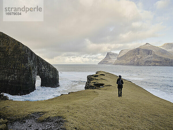 Frau beim Spaziergang in der Nähe von Drangarnir auf den Färöer Inseln
