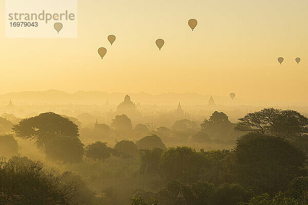 Antike Tempel und Heißluftballons bei nebligem Sonnenaufgang  Bagan  Ma