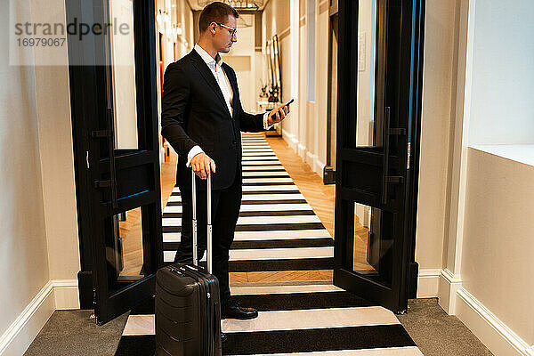 Geschäftsmann benutzt Smartphone im Hotelkorridor