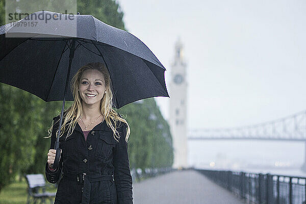 Blonde Frau geht im Regen durch eine kanadische Stadt
