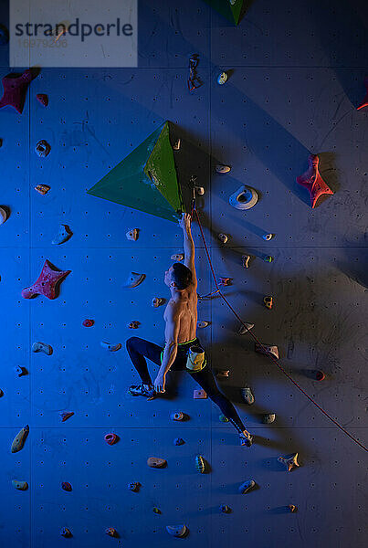 Männlicher Boulderer plant Kletterroute an der Wand