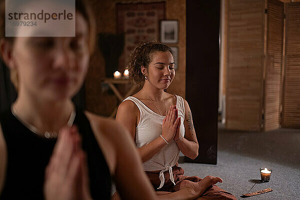 Fröhliche Frau meditiert in der Nähe eines Freundes im Studio