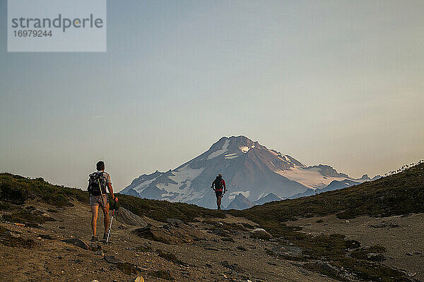 Zwei Wanderer klettern in der Morgendämmerung auf den Gipfel des Glacier Peak.