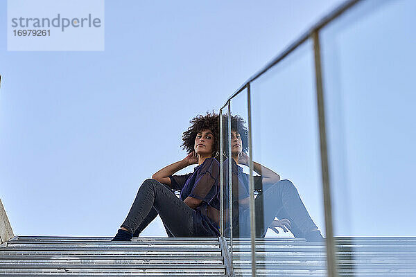 Frau mit Afro-Haar sitzt auf einer Treppe