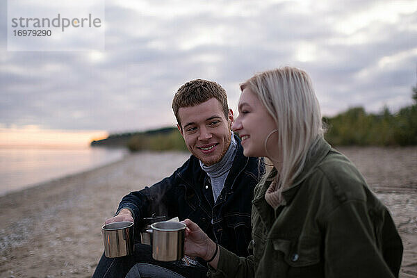 Glückliches Paar genießt Tee bei Sonnenuntergang