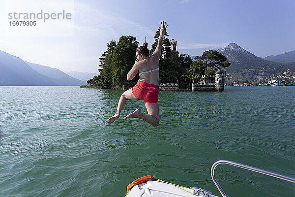 Ein Mädchen springt von einem Boot in einen See in Italien.