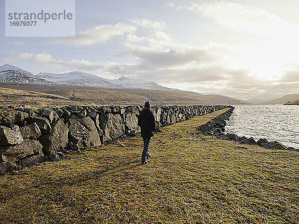 Frau  die in Haldarsvík auf den Färöer-Inseln am Steg entlanggeht