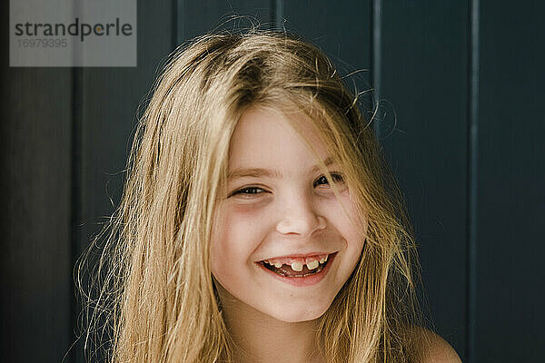 Nahaufnahme eines lächelnden jungen Mädchens mit fehlenden Zähnen