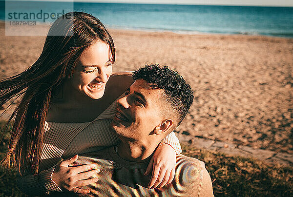Junges Paar in der Liebe umarmt und lächelnd am Strand