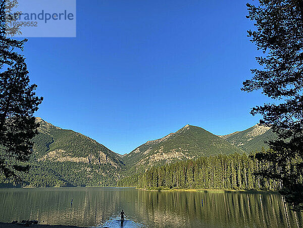 Ein Mann watet im Morgengrauen in einen See im ländlichen Montana.