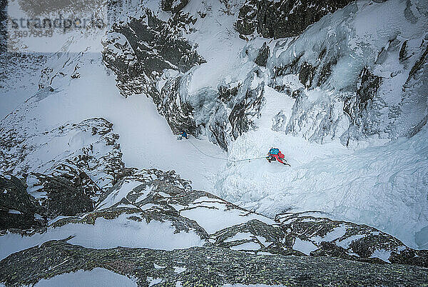 Ein alpiner Eiskletterer erklimmt eine gefrorene Schlucht in Maine