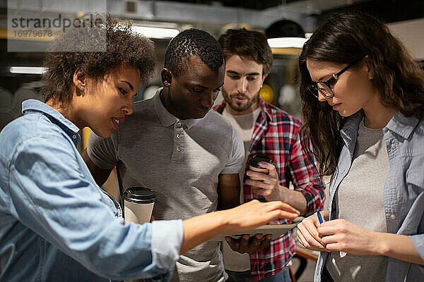 Seriöses multiethnisches Team beim Durchsuchen von Projektdaten auf einem Tablet