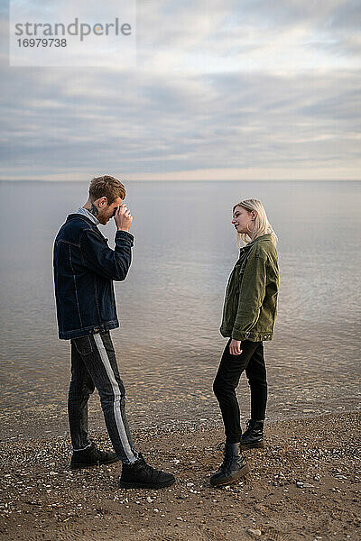 Mann fotografiert seine Freundin am Seeufer