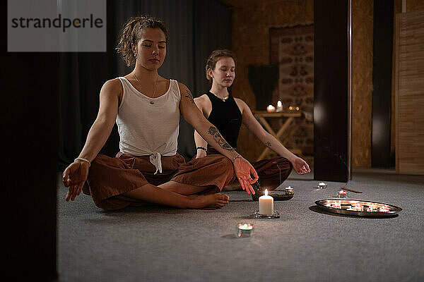 Meditierende Frauen in der Nähe brennender Kerzen