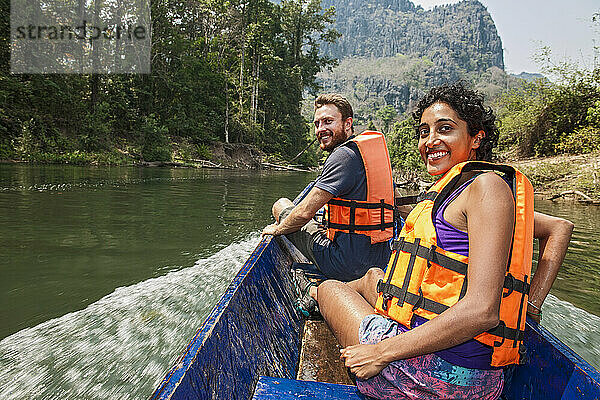 Junges Paar genießt eine Fahrt auf einem Longtailboot in Laos