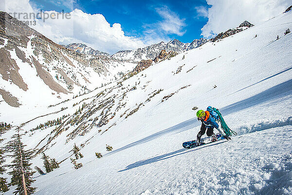 Mann beim Snowboarden im kalifornischen Backcountry mit Kletterseil