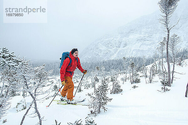 Mann beim Skifahren durch ein Geröllfeld in den Alpen
