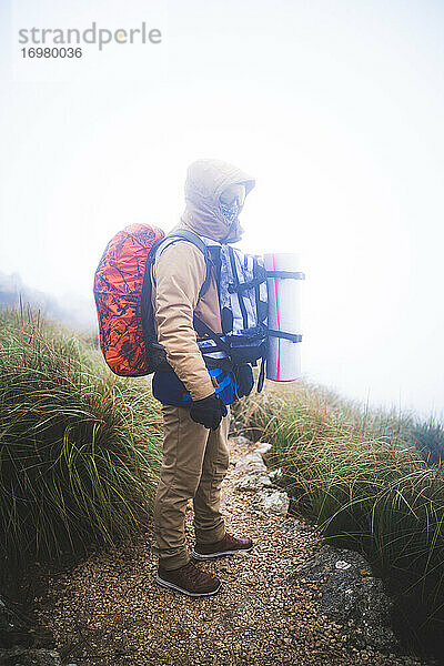 Wanderer  der mitten auf einem Weg bei Nebel in die Kamera schaut