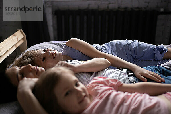 Glückliche Mutter und Töchter auf dem Bett liegend