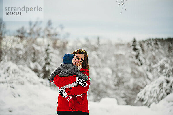 Großmutter hält Enkelkind Baby draußen im Schnee im Winter Norwegen