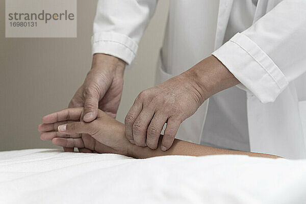 ein Arzt misst den Puls eines Patienten am Handgelenk