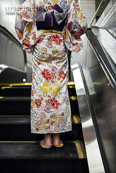 Junge Frau im japanischen Kimono auf einer Rolltreppe