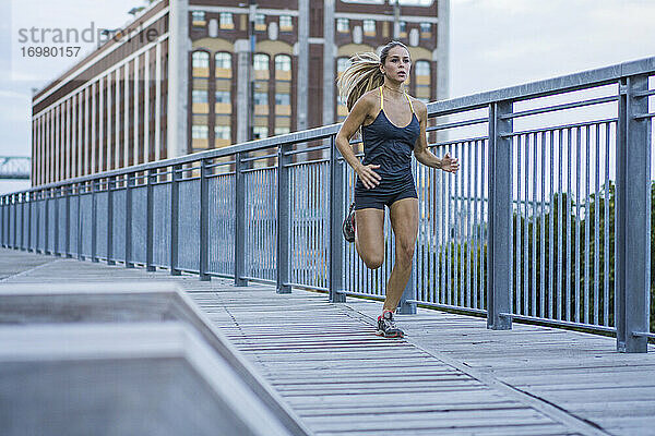 Weibliche Athletin läuft auf städtischer Promenade