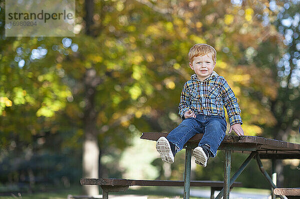 Kleinkind Junge 3 bis 4 Jahre alt sitzt auf dem Rand des Picknick-Tisch lächelnd