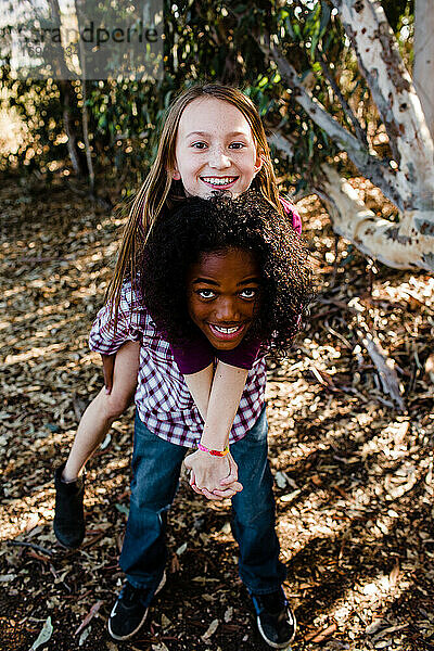 Bruder und Schwester fahren im Park in Chula Vista Huckepack