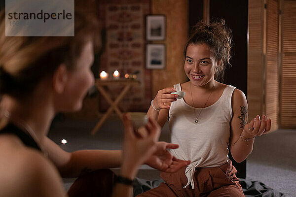 Fröhliche Frau mit Tee im Gespräch mit einem Yogalehrer