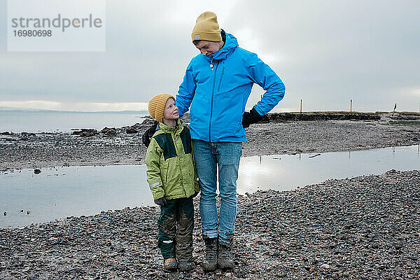 Vater und Sohn standen zusammen am Strand und waren mit Schlamm bedeckt und lächelten.
