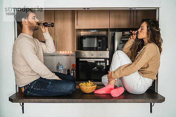 Junger Mann und Frau trinken Bier und essen Chips
