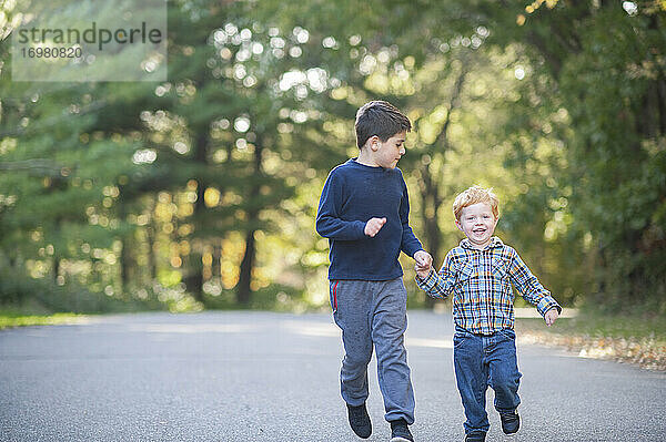 Zwei Brüder laufen lächelnd eine Straße entlang