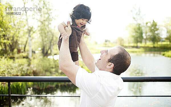 Vater hält seine Tochter auf einer Parkbrücke in die Luft
