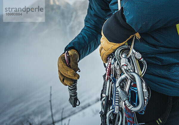 Ein Mann sortiert während einer Wintertour seine Kletterausrüstung aus Fels und Eis