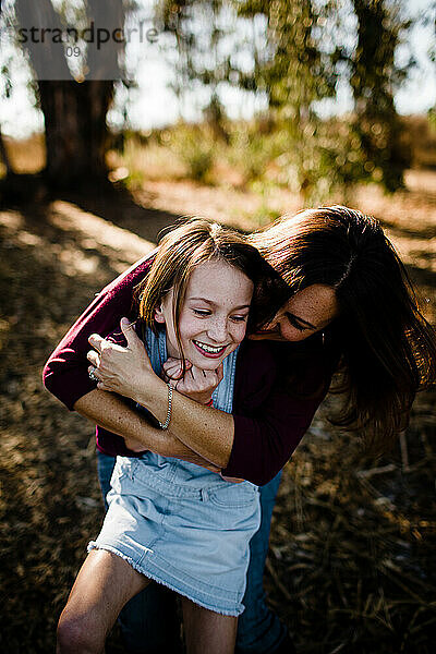 Mutter umarmt lachende Tochter im Park in Chula Vista