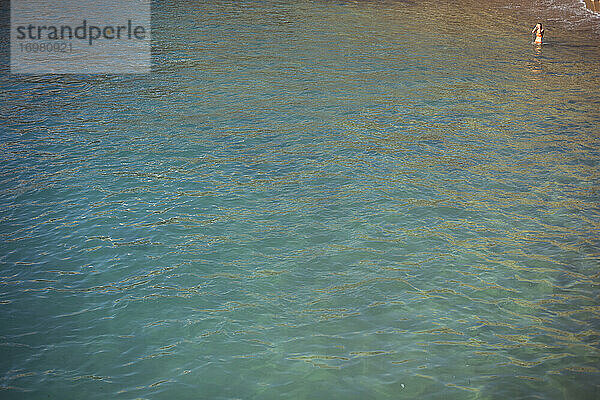 Schönes blaues Meer mit einzelner Frau  die in der Ecke des Rahmens badet