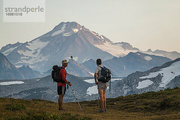 Zwei Wanderer klettern in der Morgendämmerung auf den Gipfel des Glacier Peak.