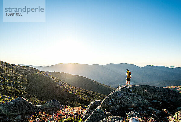Mann blickt bei Sonnenaufgang über die Weißen Berge bei einem Trailrun