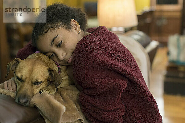 Elfjähriges gemischtrassiges Mädchen umarmt einen kleinen braunen Hund