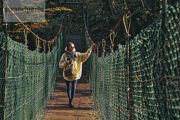 Junge Frau beim Überqueren einer Hängebrücke
