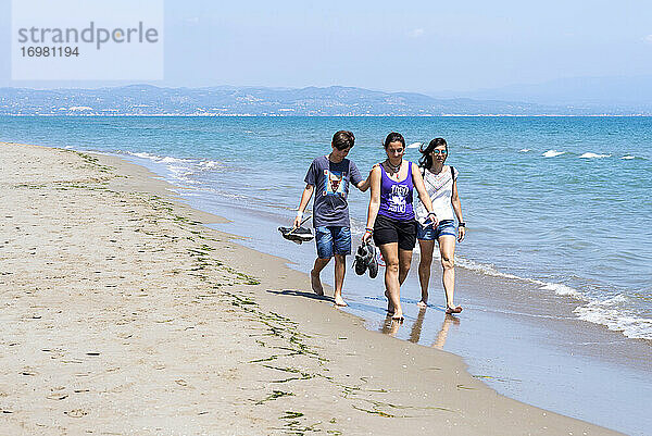 Frontansicht einer Familie  die an einem sonnigen Tag barfuß am Strand läuft