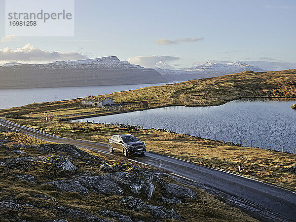 Autofahrt auf einer Landstraße bei Sonnenuntergang auf den Färöer Inseln