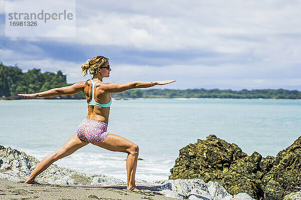 Weiblicher Reisender macht Yoga am Strand