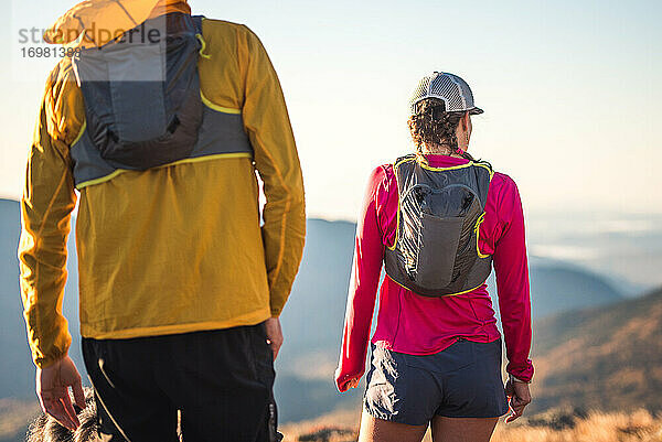 Mann und Frau  die als Trailrunner stehen und auf die Berge schauen