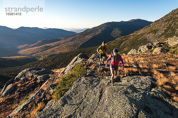 Mann und Frau beim Trailrunning in den Bergen bei Sonnenaufgang